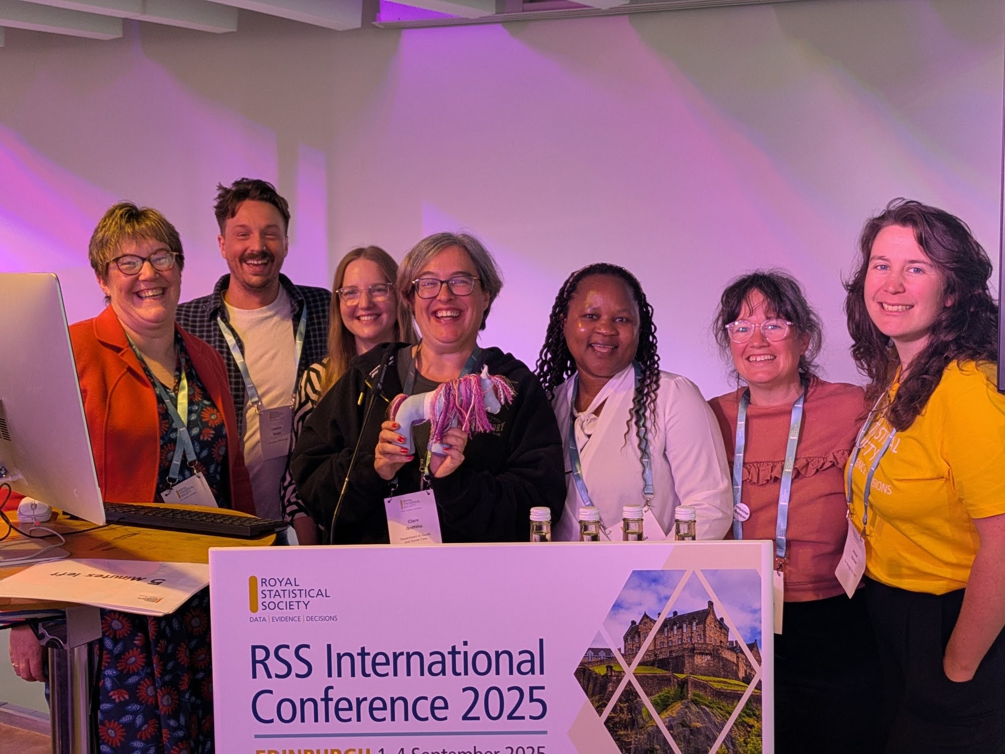 Seven people smiling behind a sign for the Royal Statistical Society International Conference 2025.